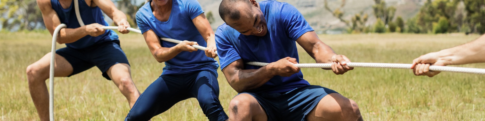 Adventures Corporate People playing tug of war during obstacle training course