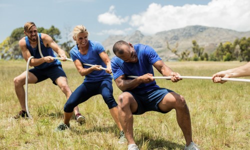 Adventures Corporate People playing tug of war during obstacle training course