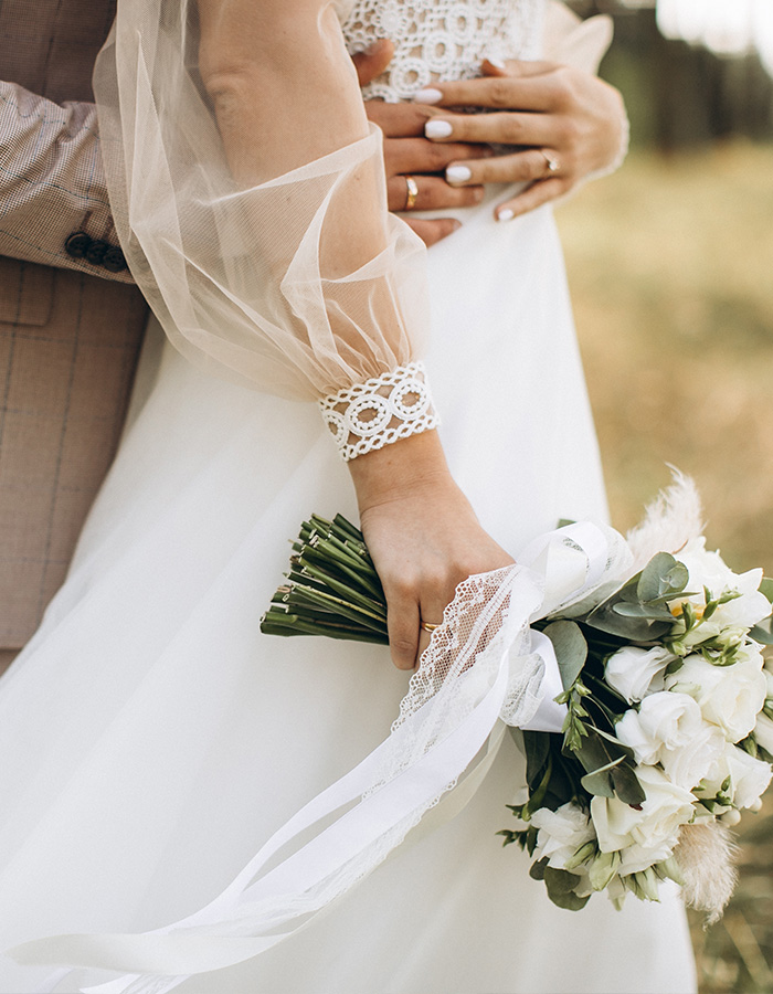 A close up of a bride holding her bouquet and the groom cuddling her