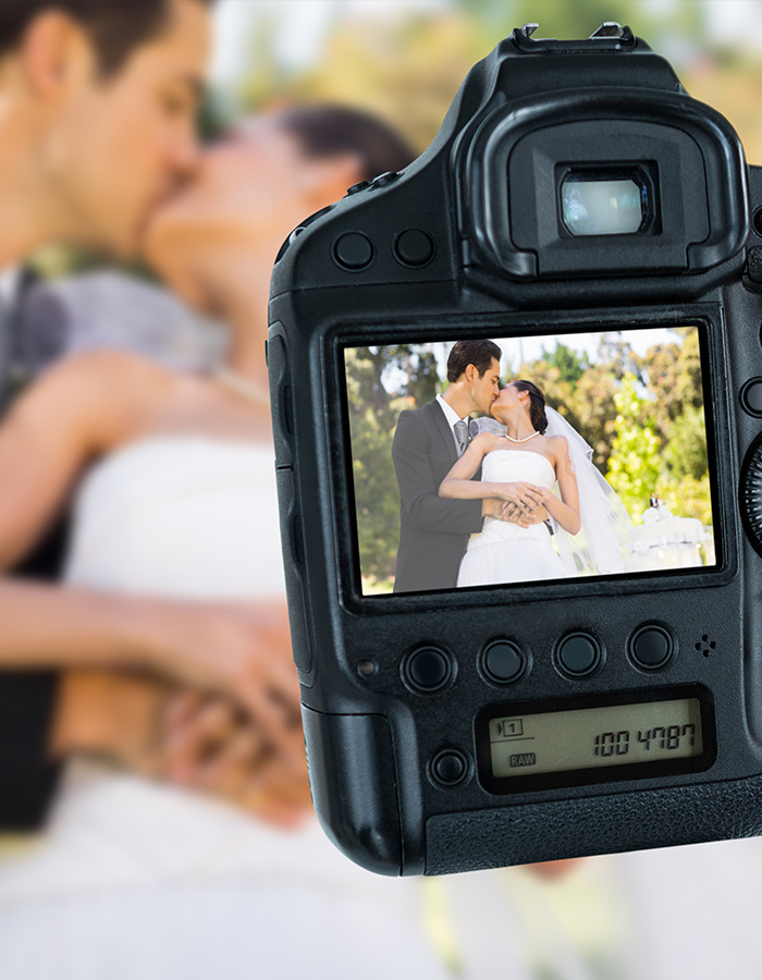 A wedding photographer taking a photo of a bride and groom.