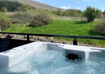 Hot tub at Glen Clova Lodges with countryside in background.